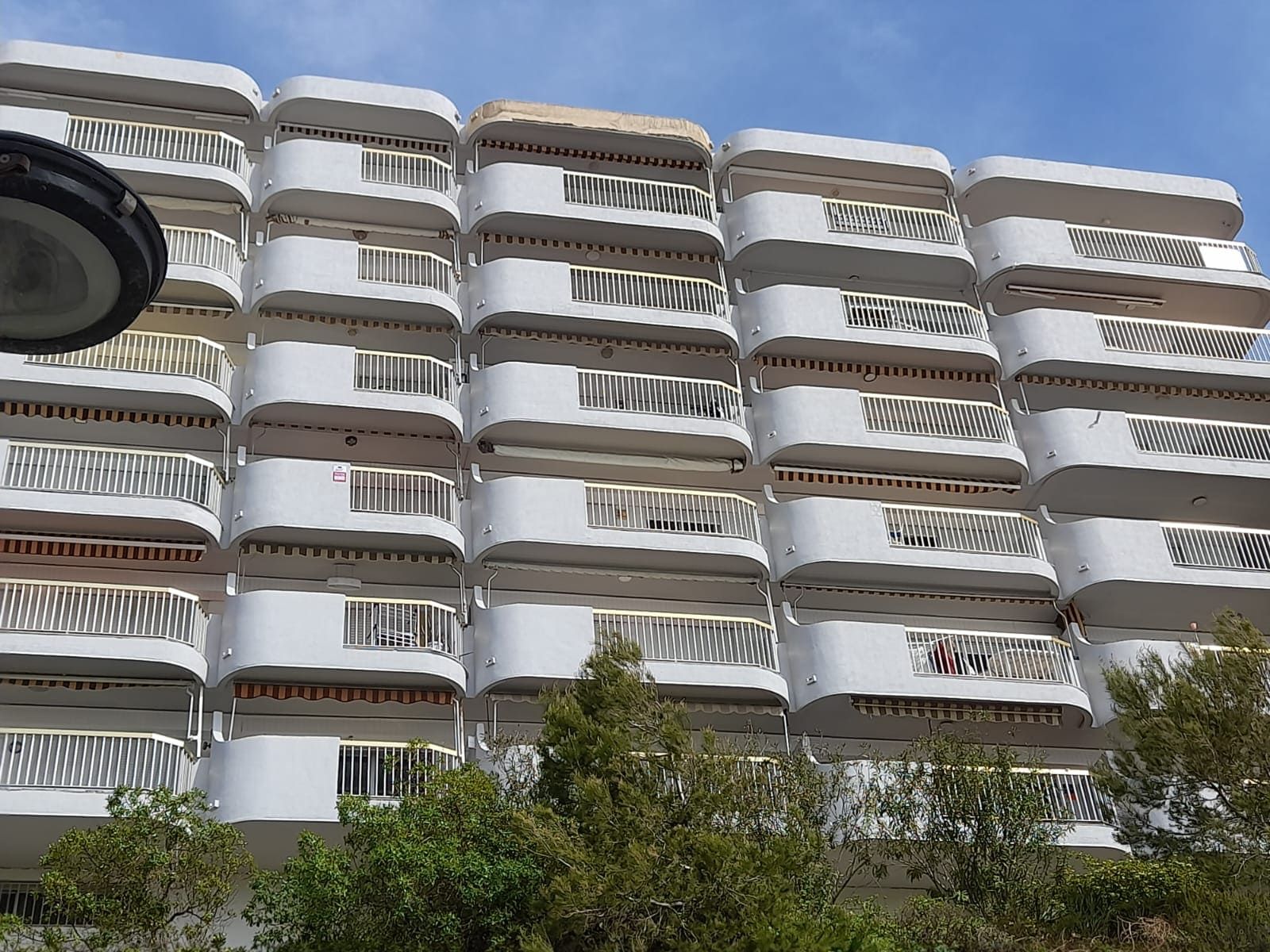 Un edificio alto con muchos balcones y árboles en el frente.