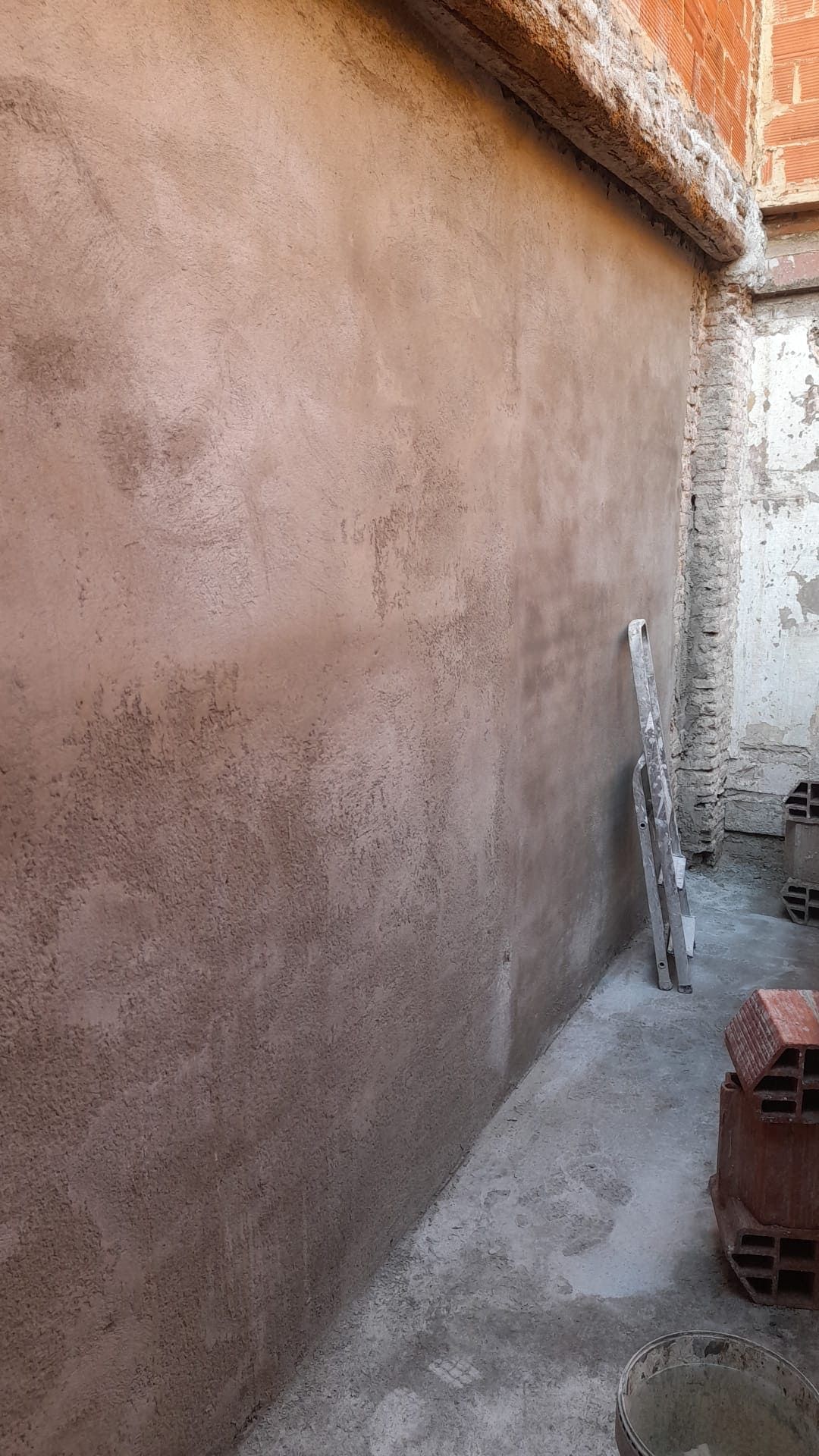 Una escalera está apoyada contra una pared en un patio trasero.