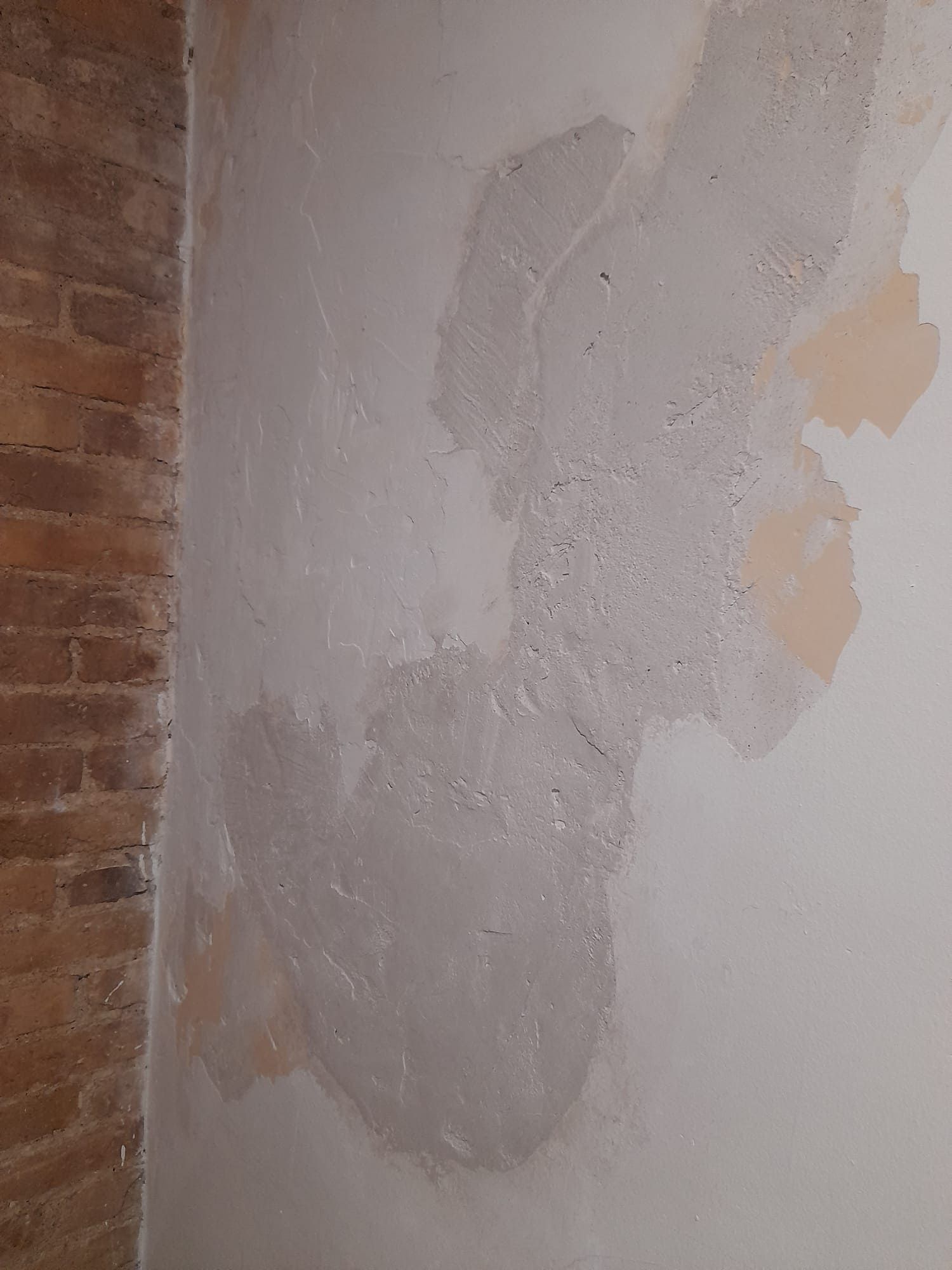 Una pared blanca con una pared de ladrillos al fondo.