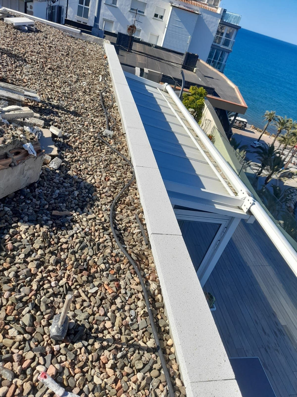 Un tejado con vista al mar y un edificio al fondo.