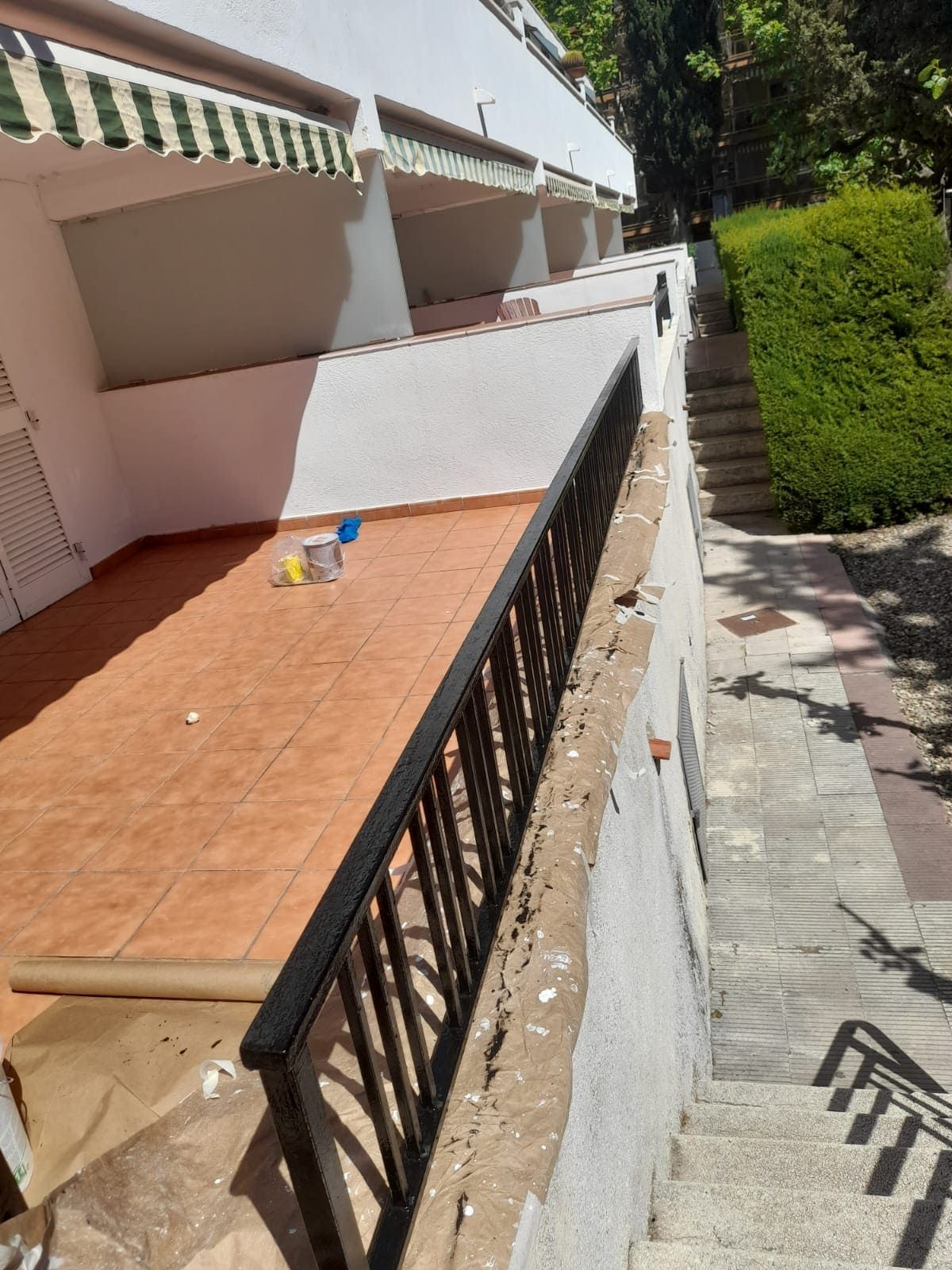 Un balcón con barandilla negra y escaleras que conducen hasta él.