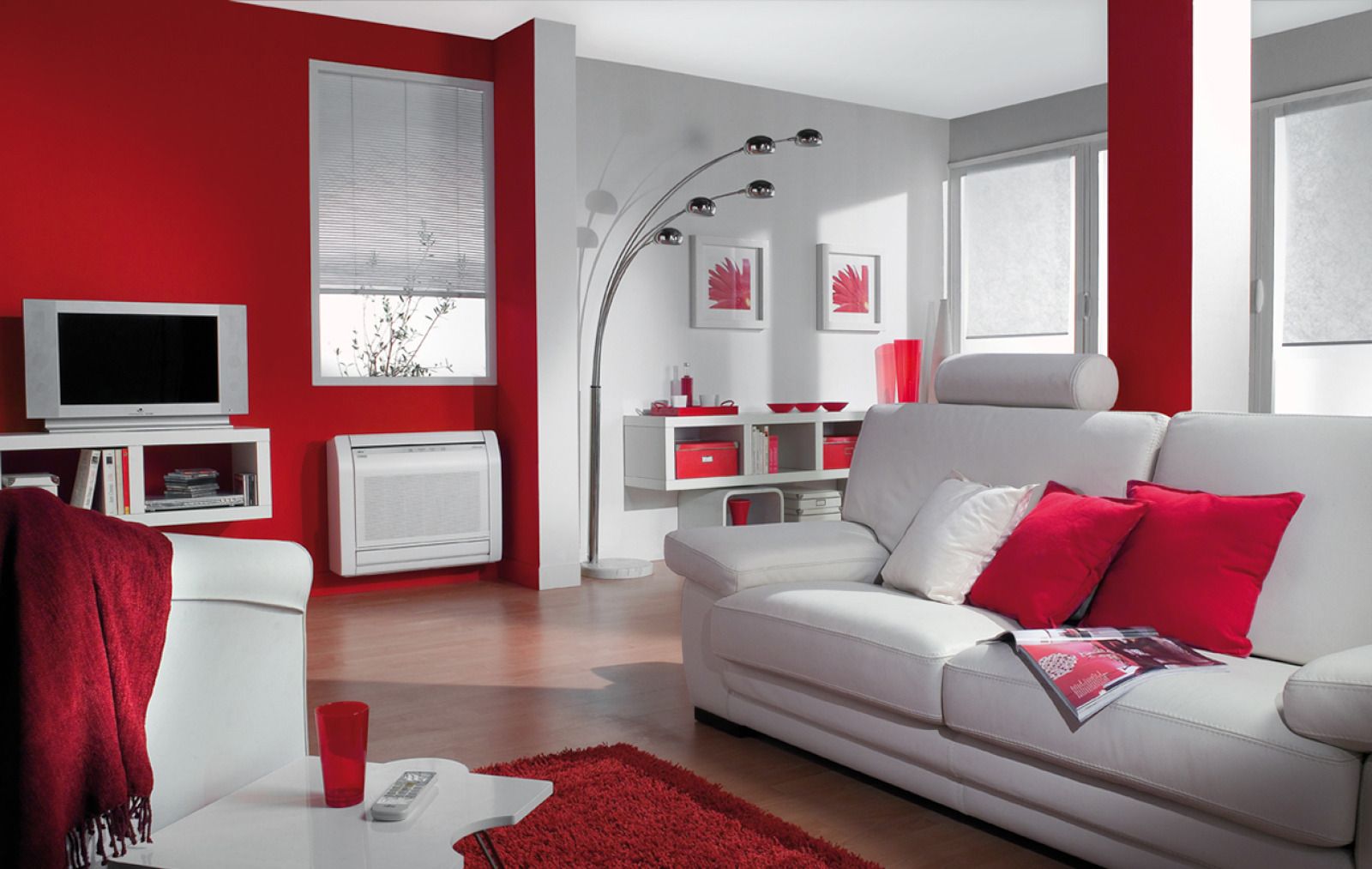 Salon moderne avec murs rouges, canapé blanc, télévision et coin bureau avec miroir