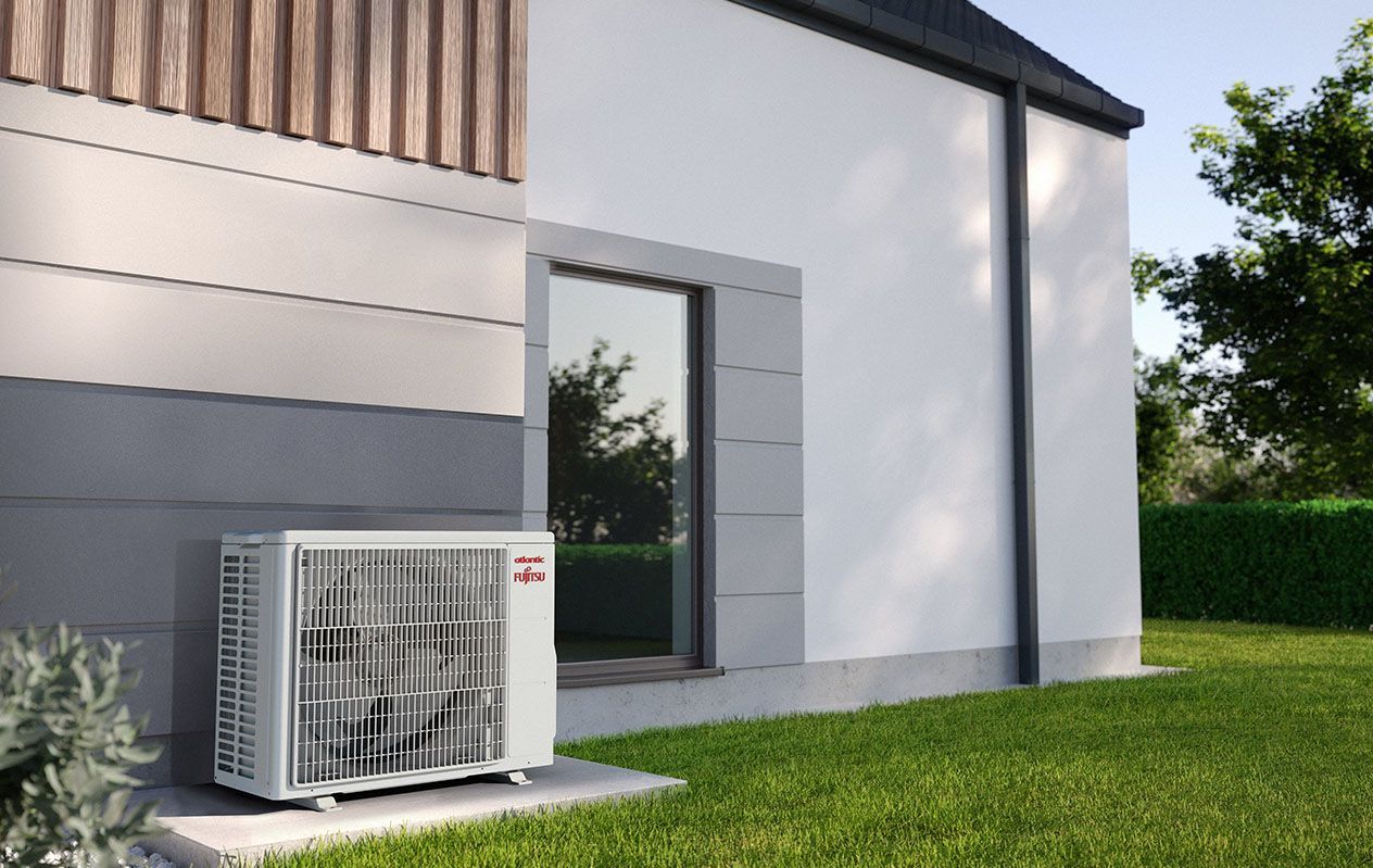 Unité de climatisation extérieure à côté d'une maison blanche moderne sur une pelouse.
