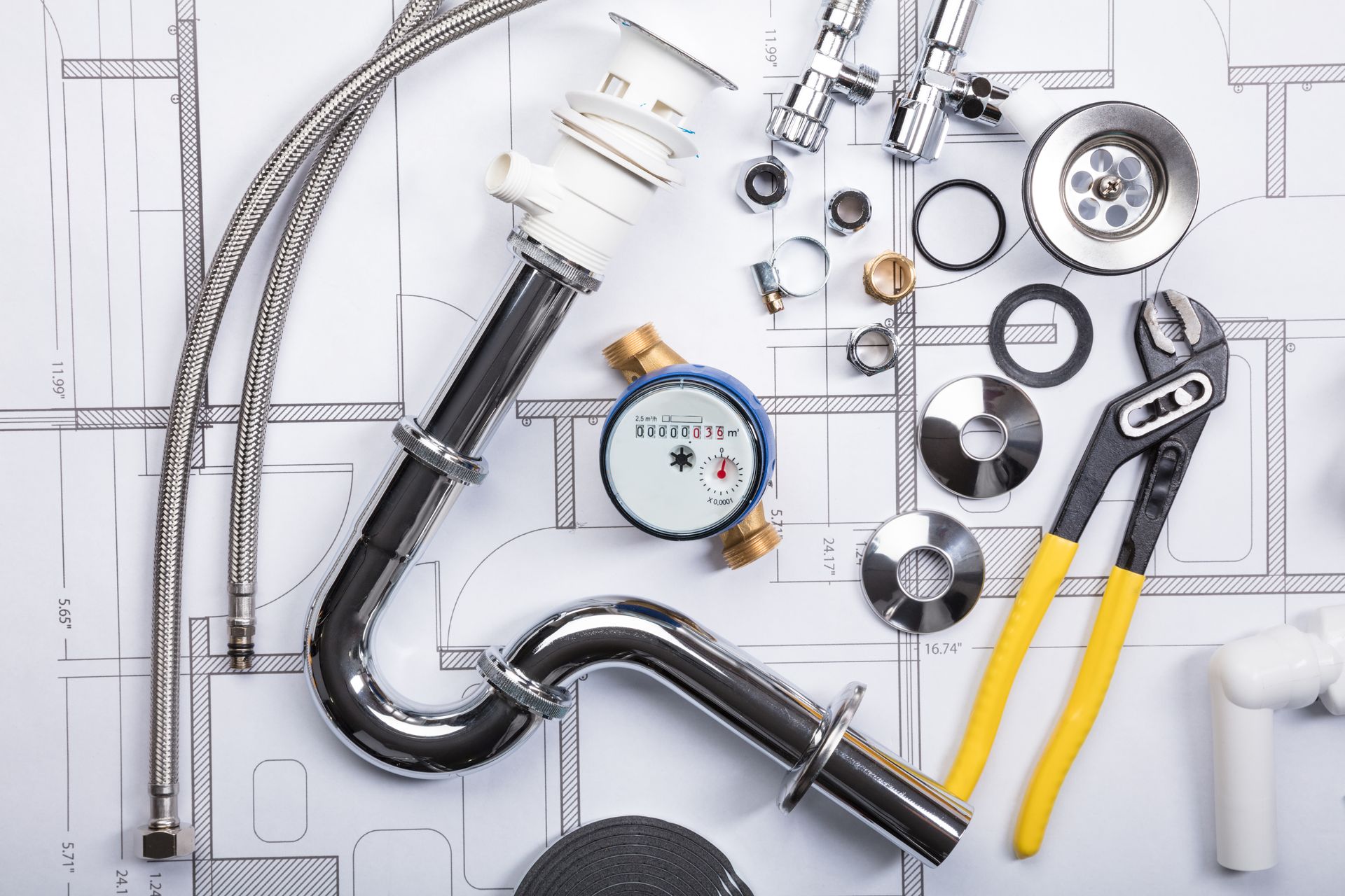 Outils de plomberie et raccords de tuyauterie figurant sur un plan, y compris clés, manomètre et tuyaux d'évacuation.