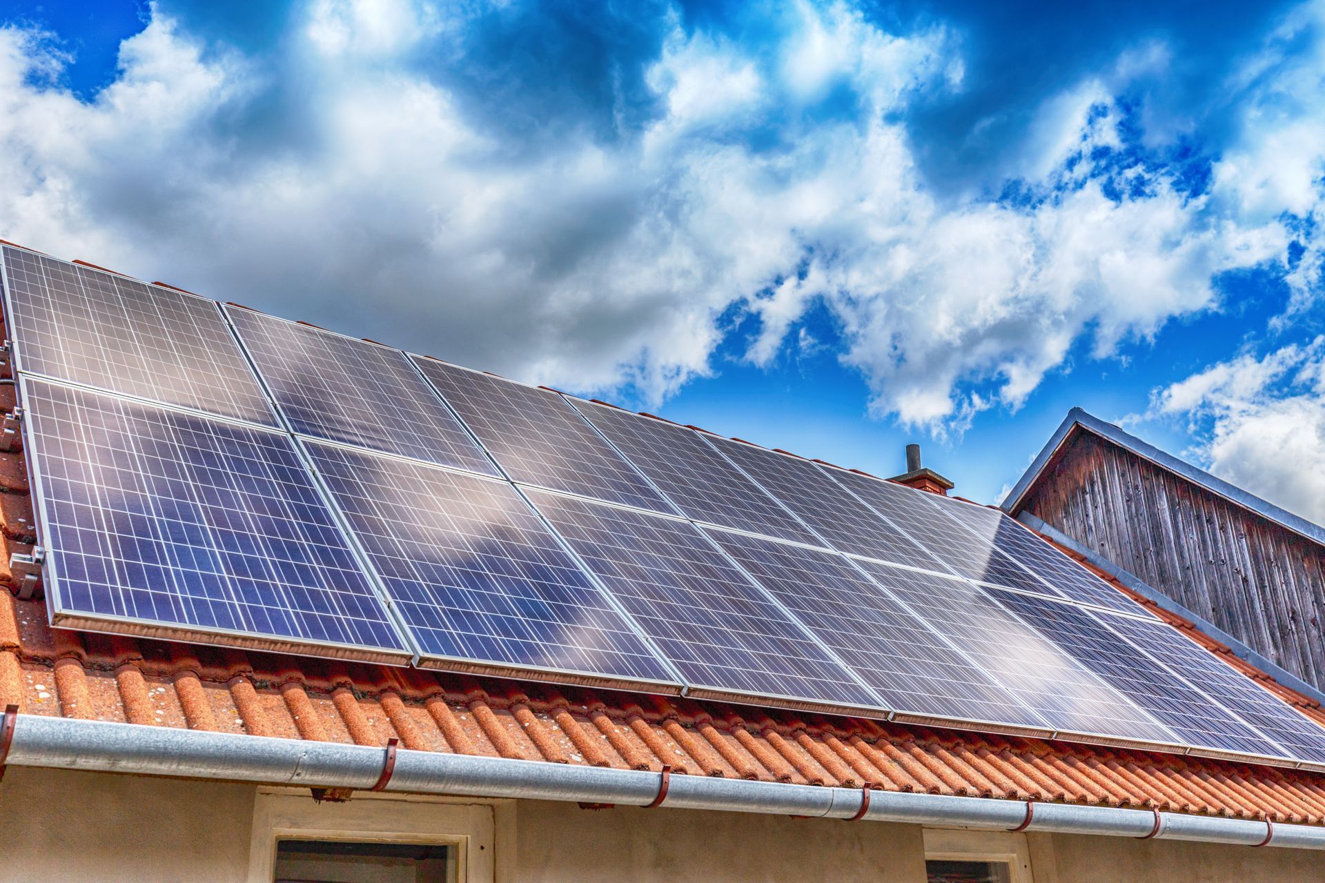 Des panneaux solaires sur le toit d'une maison sous un ciel bleu éclatant parsemé de nuages
