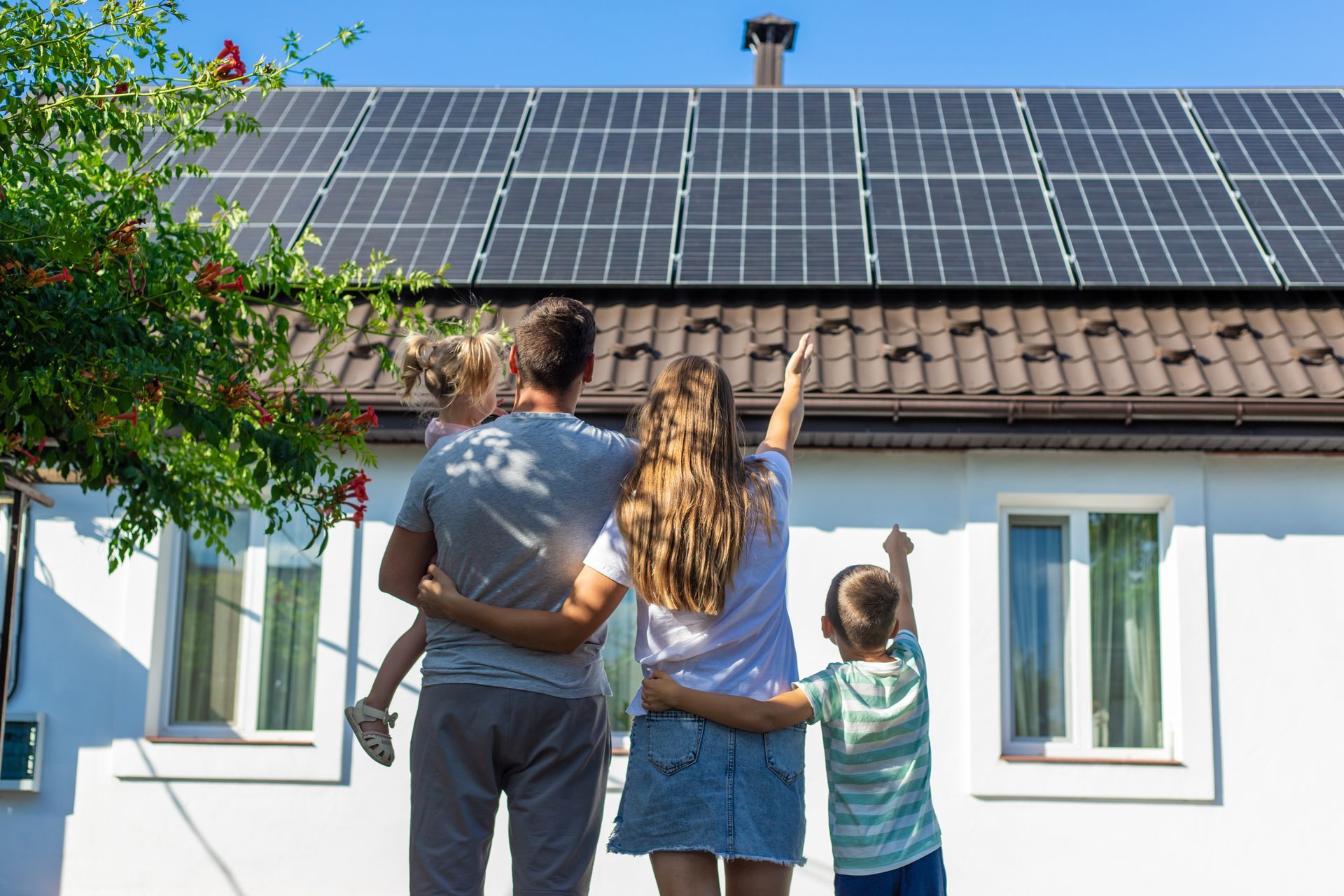 Une famille regarde les panneaux solaires sur le toit d'une maison sous un ciel bleu