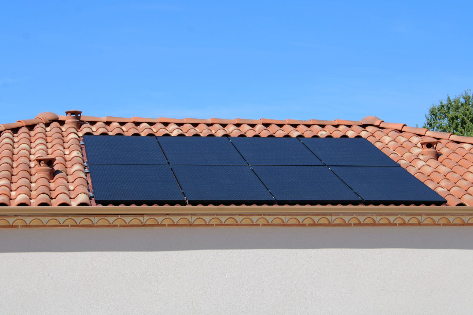 Des panneaux solaires installés sur un toit de tuiles en terre cuite sous un ciel bleu
