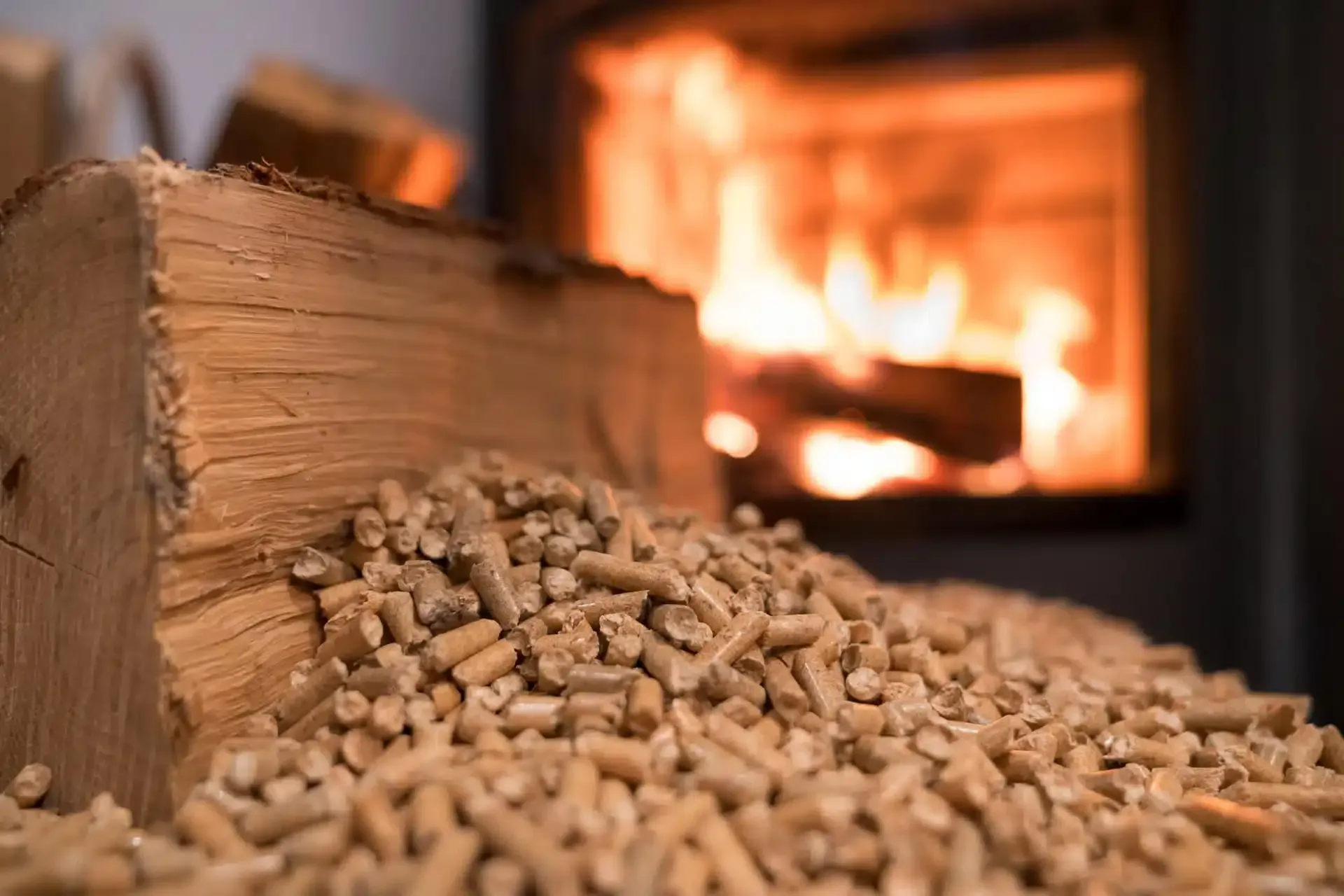 Pile de granulés de bois près d'une cheminée allumée avec des flammes incandescentes en arrière-plan