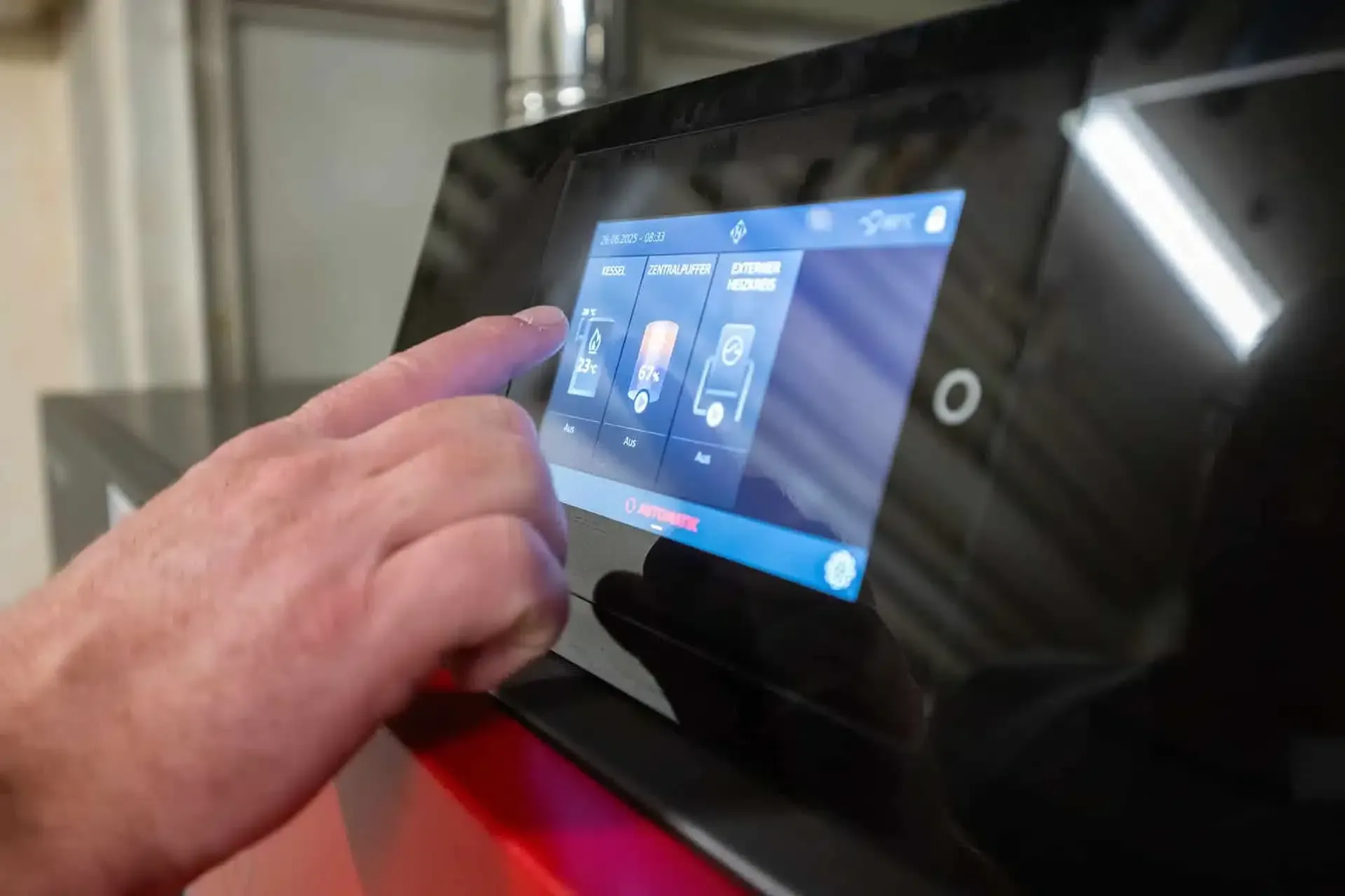 Main touchant un panneau de commande tactile à interface bleue dans un environnement intérieur faiblement éclairé