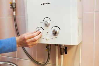 Une main tourne les boutons d'un chauffe-eau