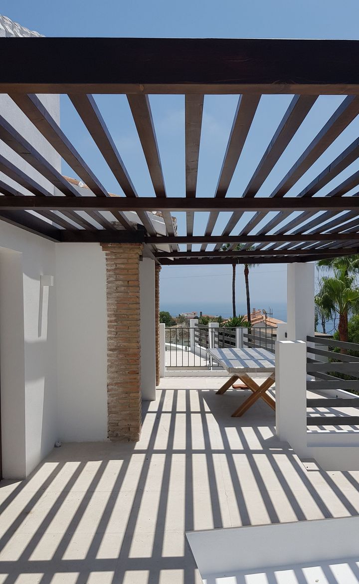 Una pérgola con una mesa y sillas debajo.