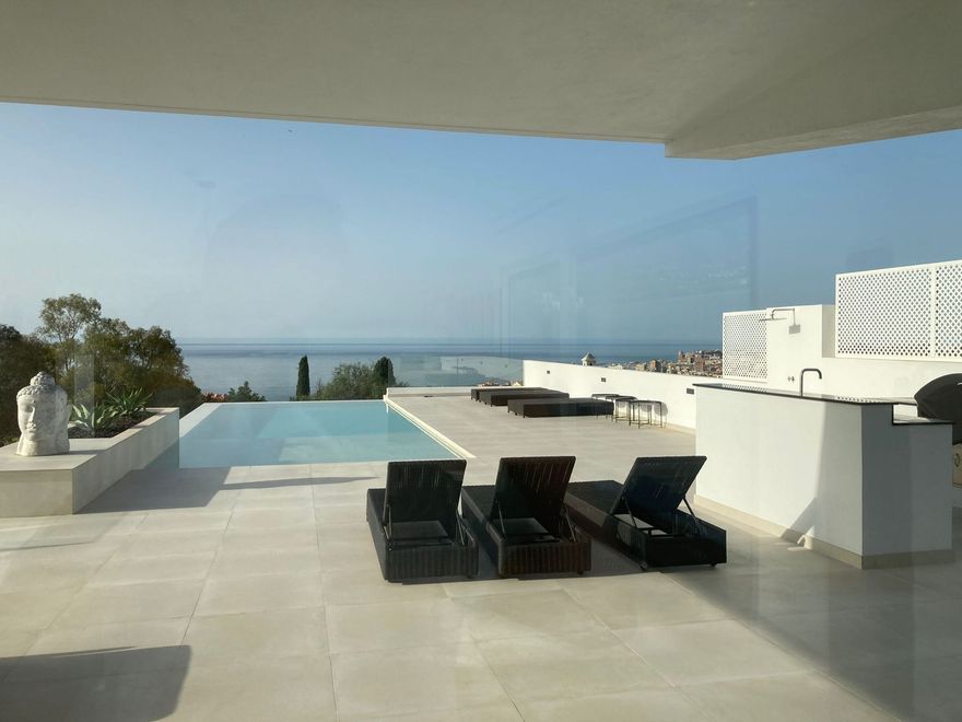 Un patio con sillas y una piscina con vista al mar.