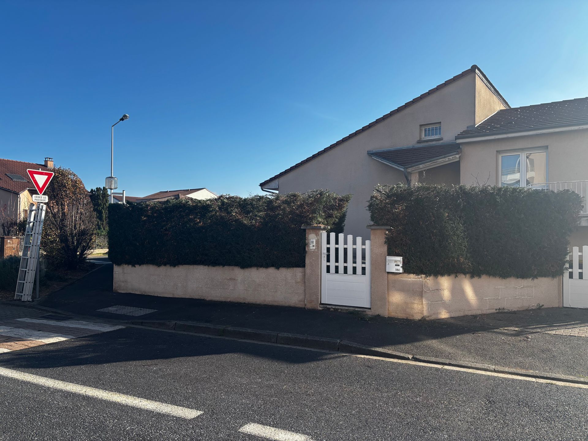Maison avec un portail et une haie le long d'une rue.