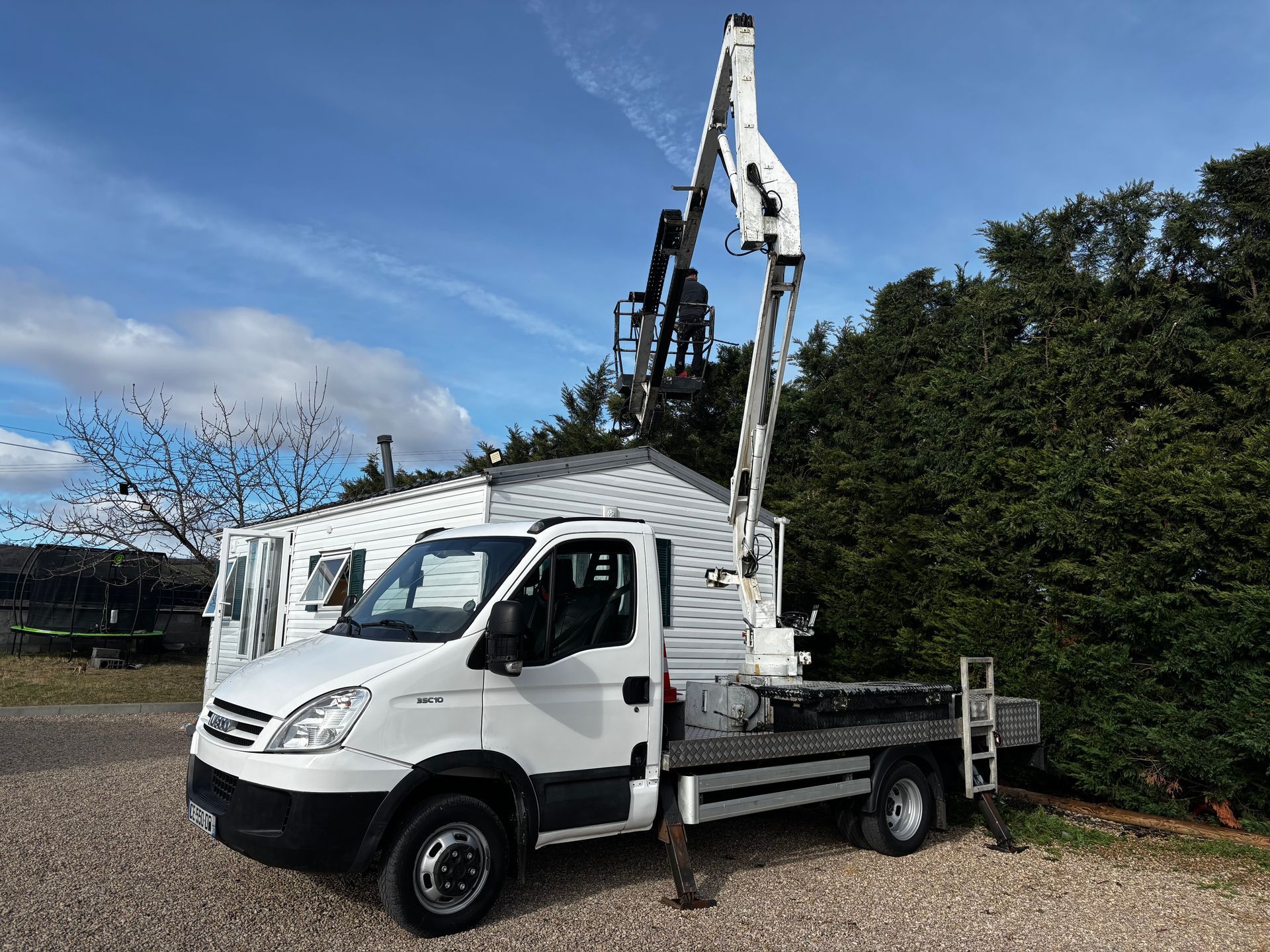 Un camion équipé d'une nacelle élévatrice travaille sur un petit bâtiment.