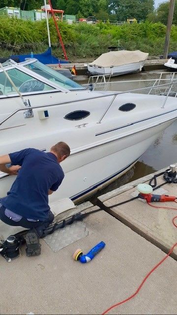 Ein Mann kniet neben einem weißen Boot