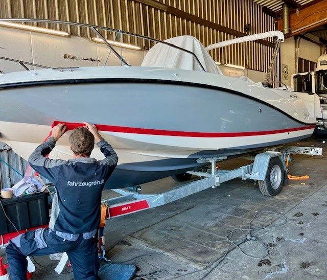 Ein Mann kniet vor einem Boot auf einem Anhänger