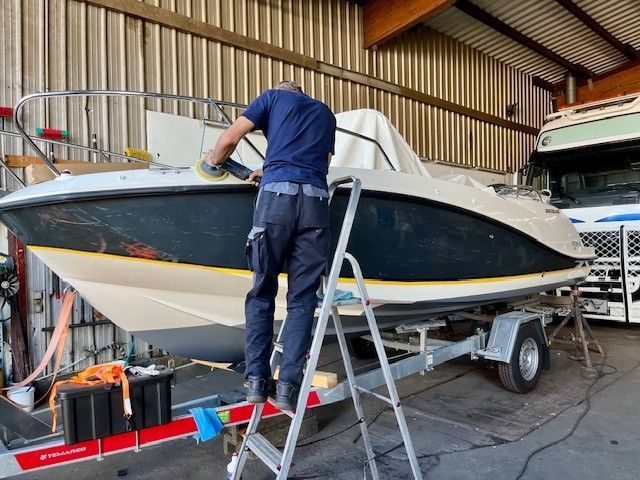 Ein Mann mit einer Gasmaske reinigt in einer Garage ein Boot.