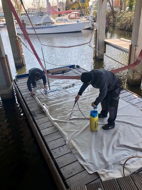 Zwei Männer arbeiten an einem Boot auf einem Dock.