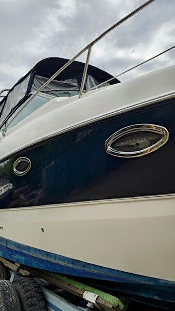 Auf einem Anhänger steht ein blau-weißes Boot.