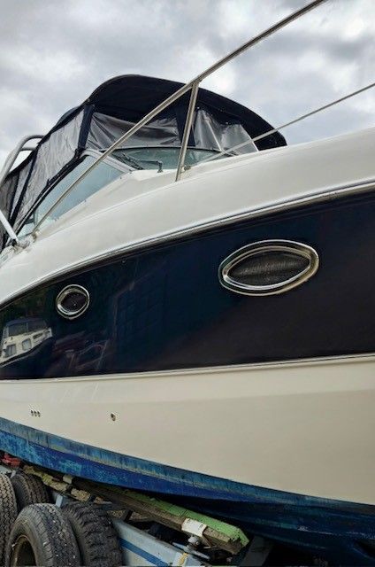 Auf einem Anhänger steht ein blau-weißes Boot.