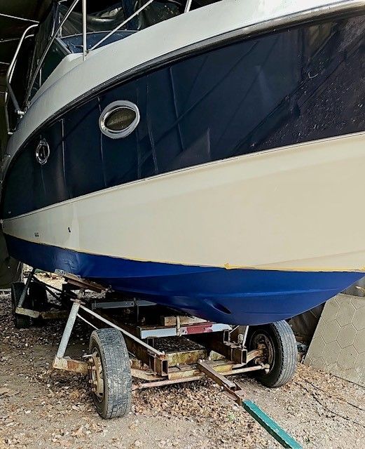 Auf einem Anhänger liegt ein blau-weißes Boot.