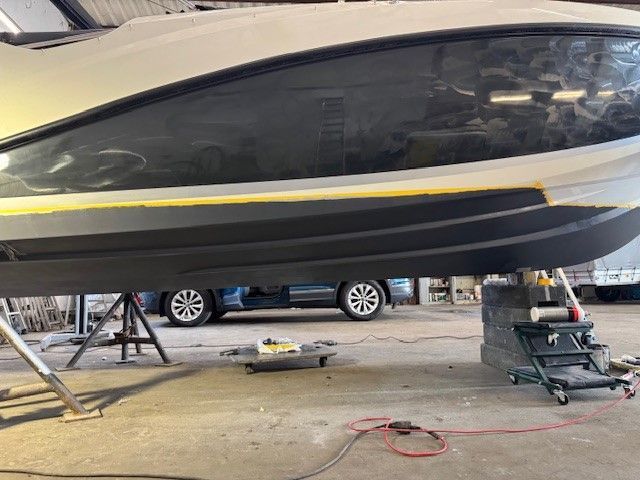 In einer Garage liegt neben einem Auto ein Boot auf dem Boden.