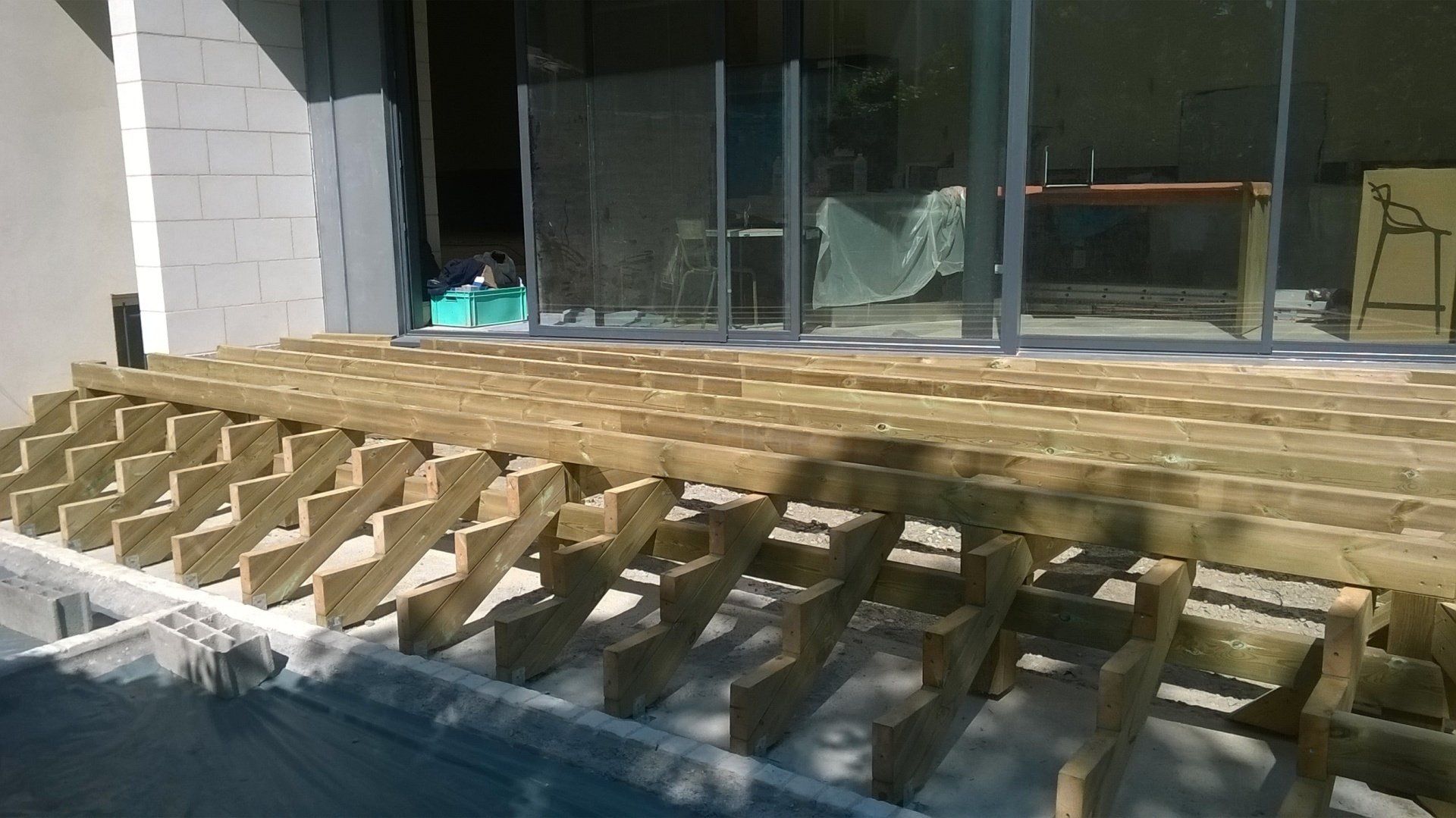 Structure en bois pour accueillir une terrasse en bois avec des marches devant des baies vitrées