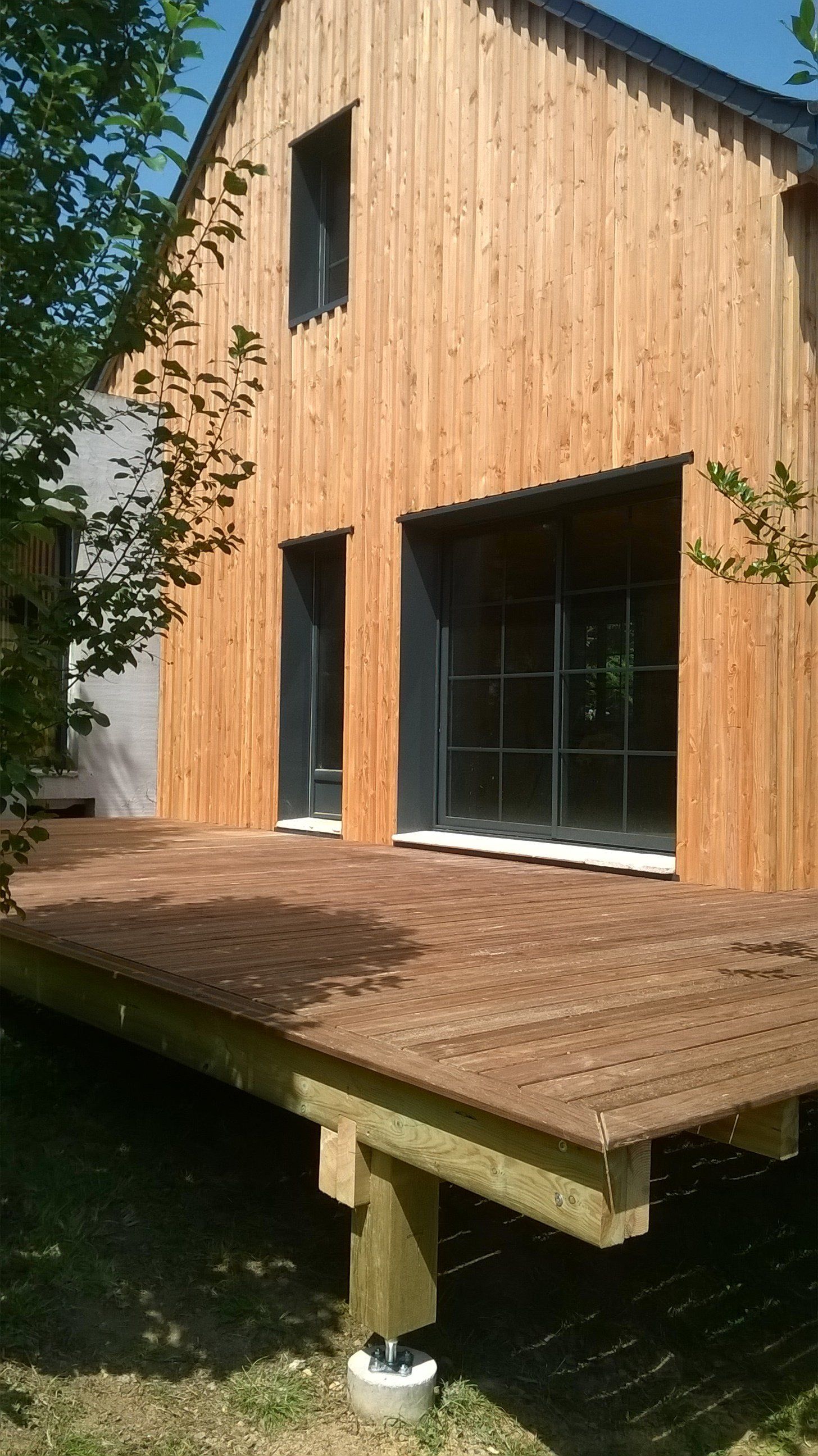 Terrasse en bois et façade en bois avec une baie vitrée gris anthracite