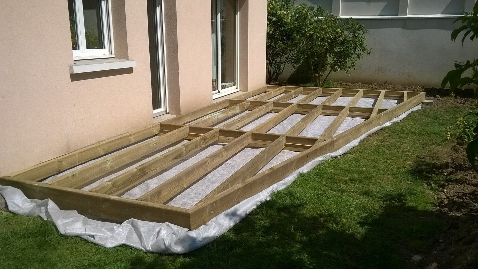 Structure en bois pour recevoir une terrasse devant les baies vitrées d'une maison