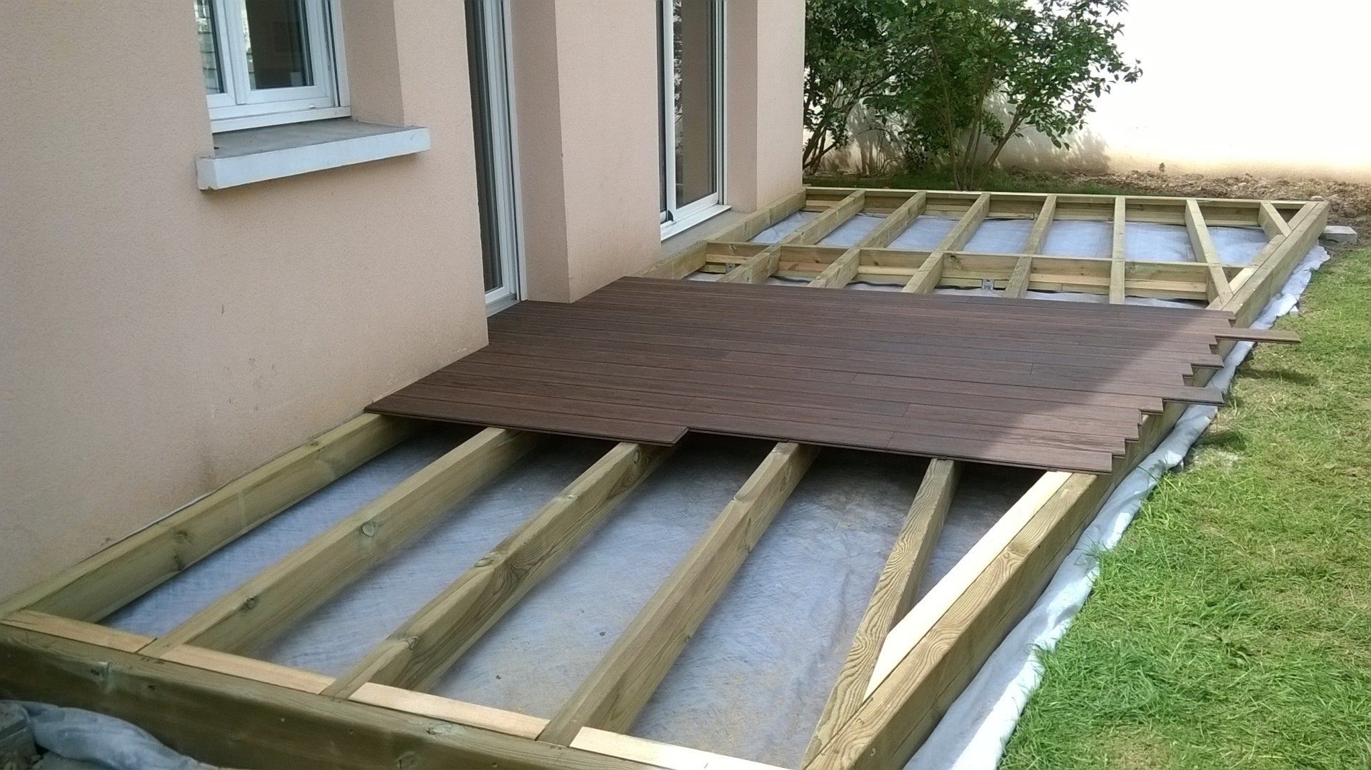 Pose en cours d'une terrasse en bois devant une maison