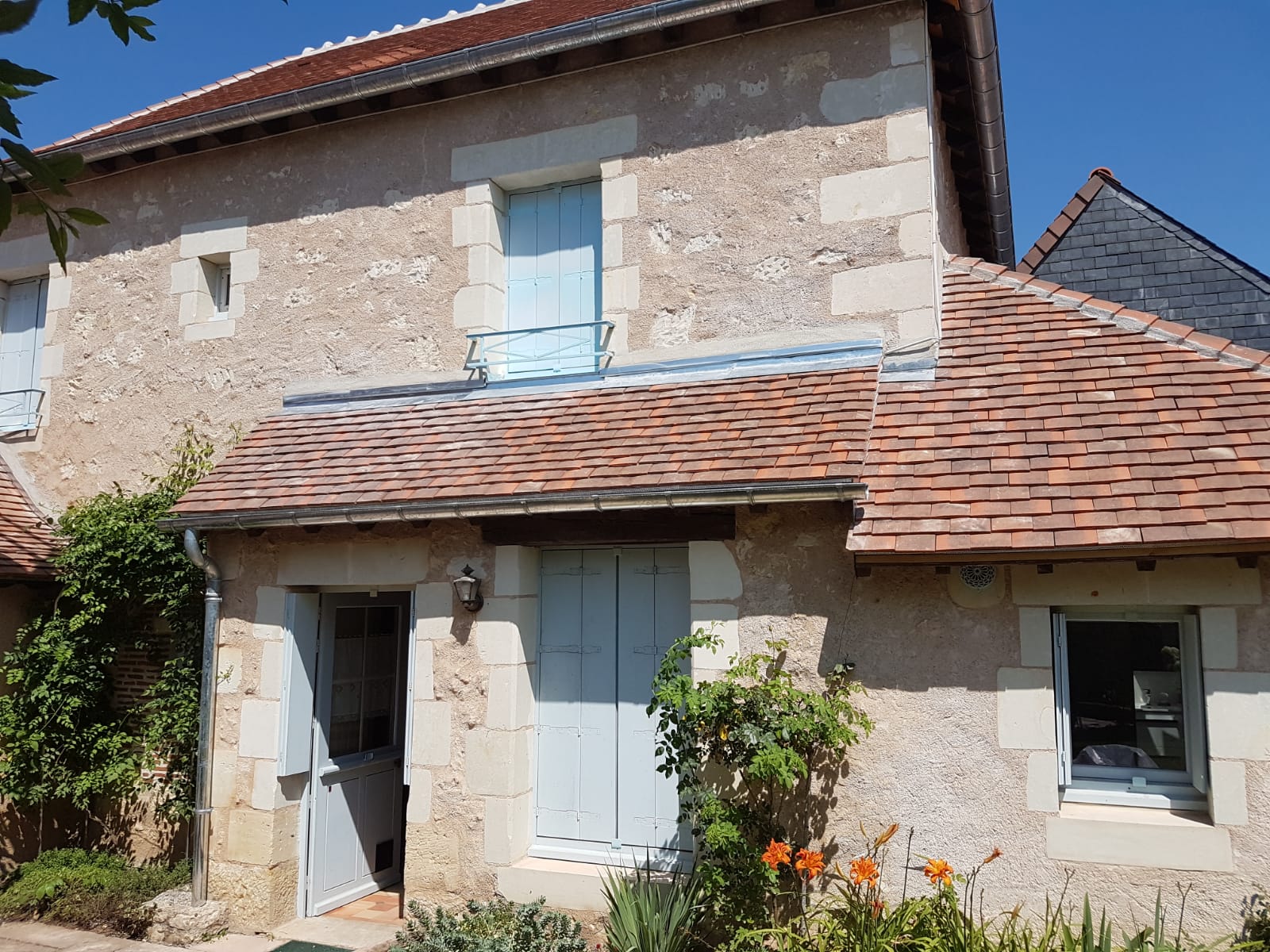 Façade d'une maison avec toiture en tuiles et volets bleus clairs