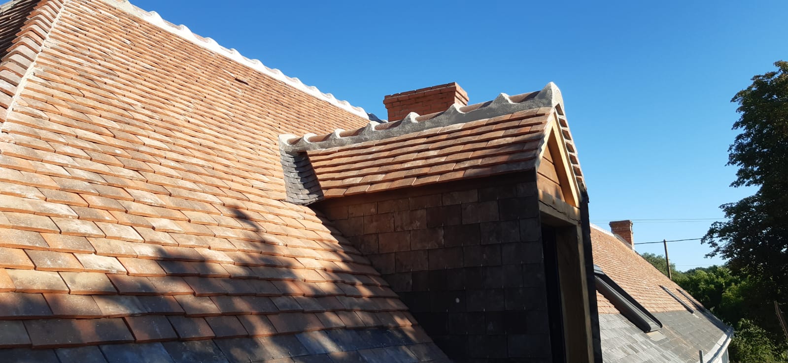 Lucarne de toit sur une toiture mixte avec de l'ardoise et des tuiles en terre cuite