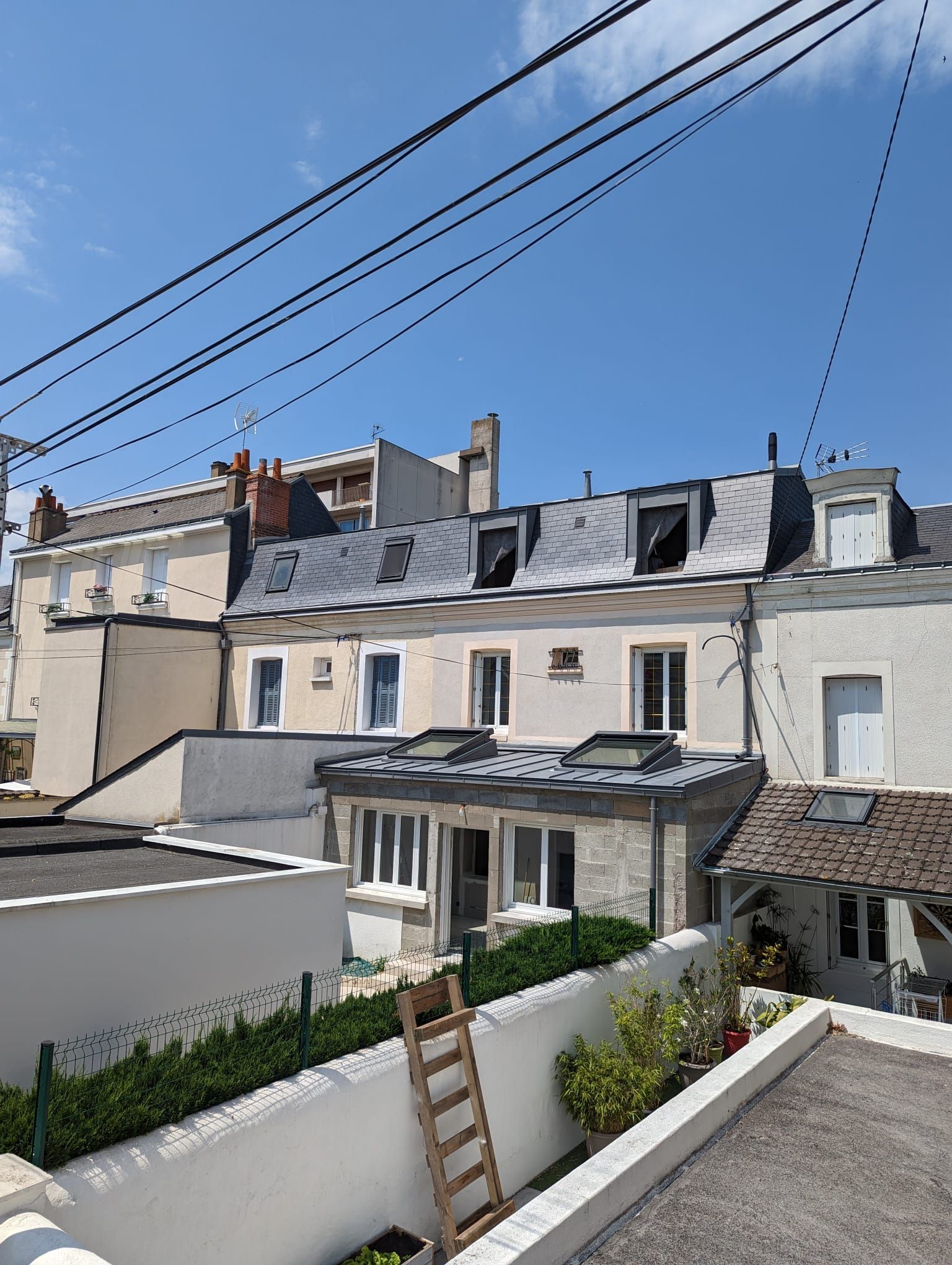 Façade supérieure d'un immeuble résidentiel à trois étages avec toit gris et fenêtres de toit