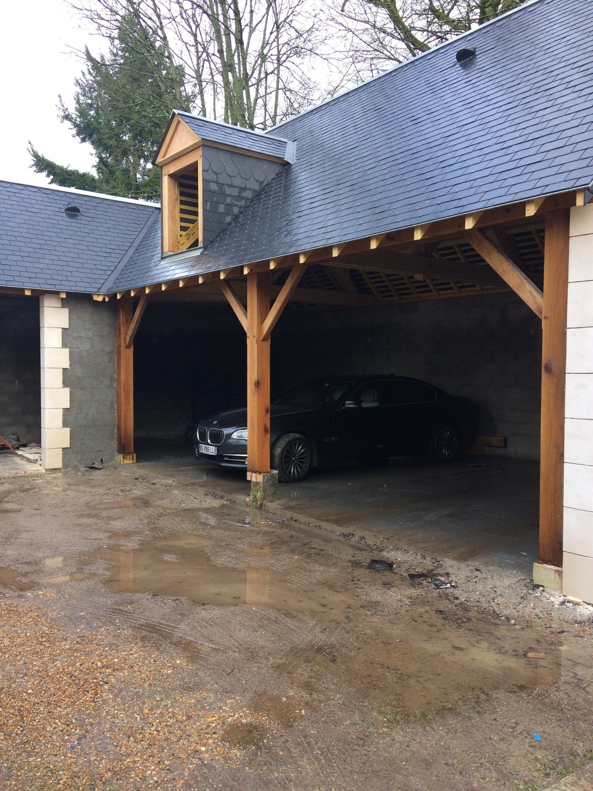 Double carport avec structure en bois et couverture en ardoise avec une voiture garée