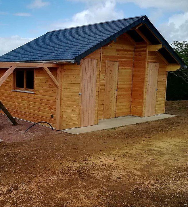 Cabane avec ossature en bois avec trois portes et une fenêtre et toiture en ardoise