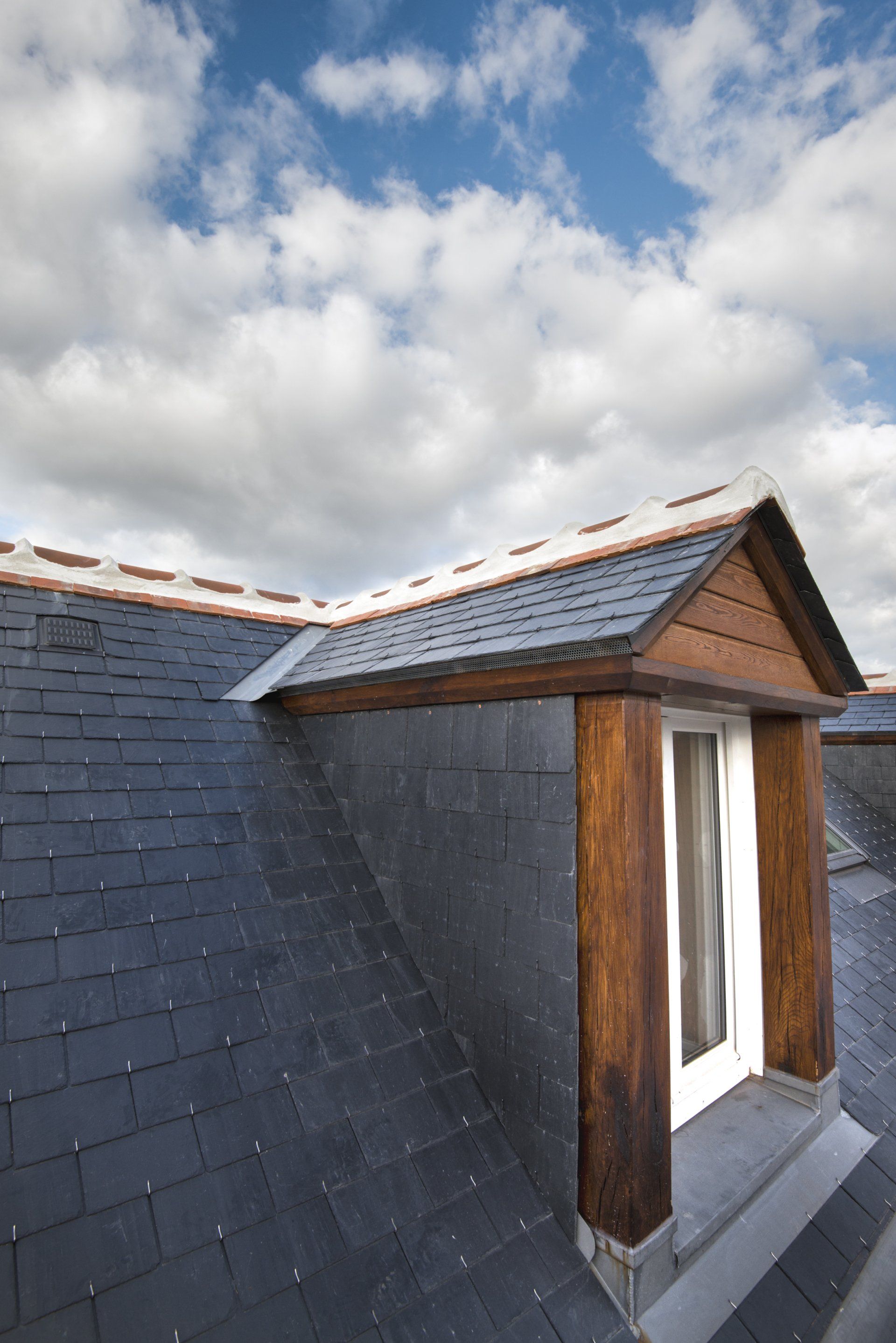 Gros plan sur une lucarne de toit avec une toiture en ardoise