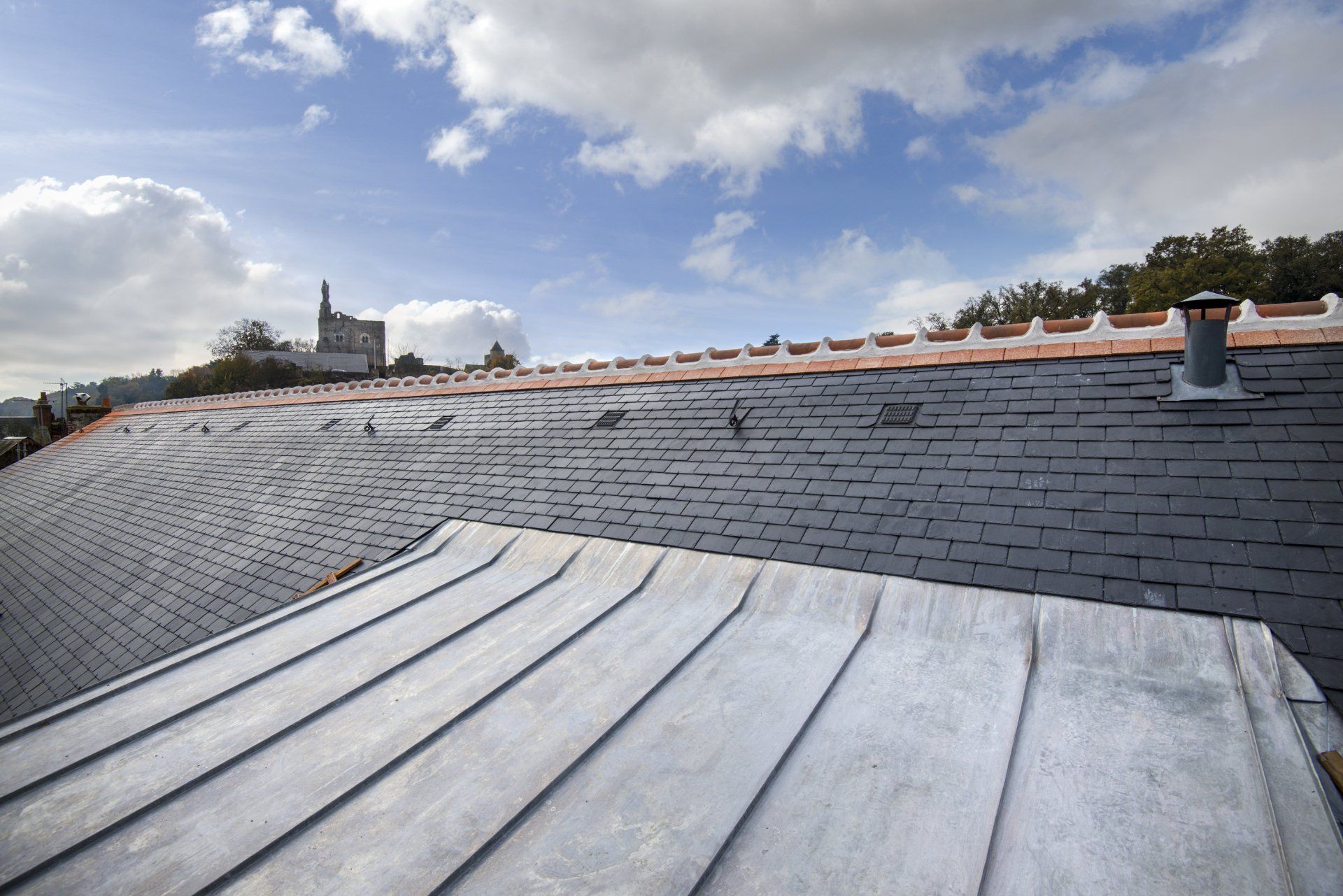 Toit mixte en métal et ardoise avec un conduit de cheminée