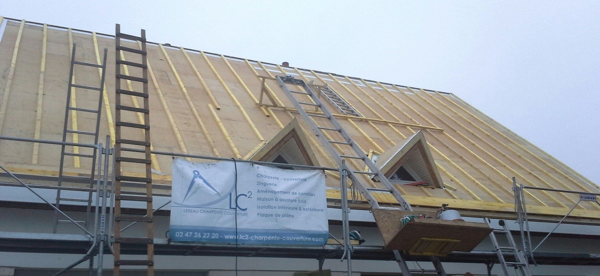 Travaux de couverture et d'isolation sur une toiture avec une banderole LC²