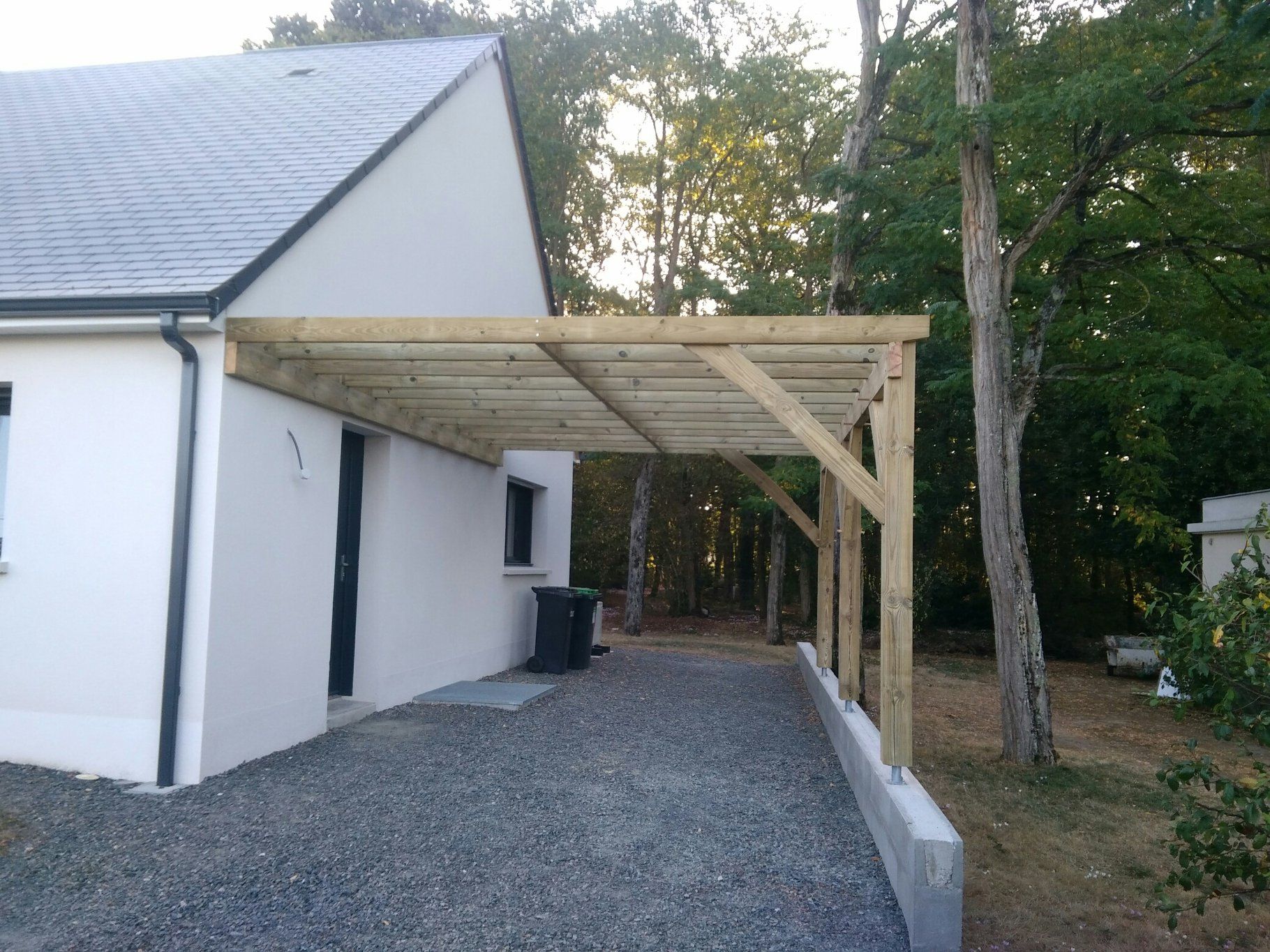 Pergola en bois adossée au pignon d'une maison blanche