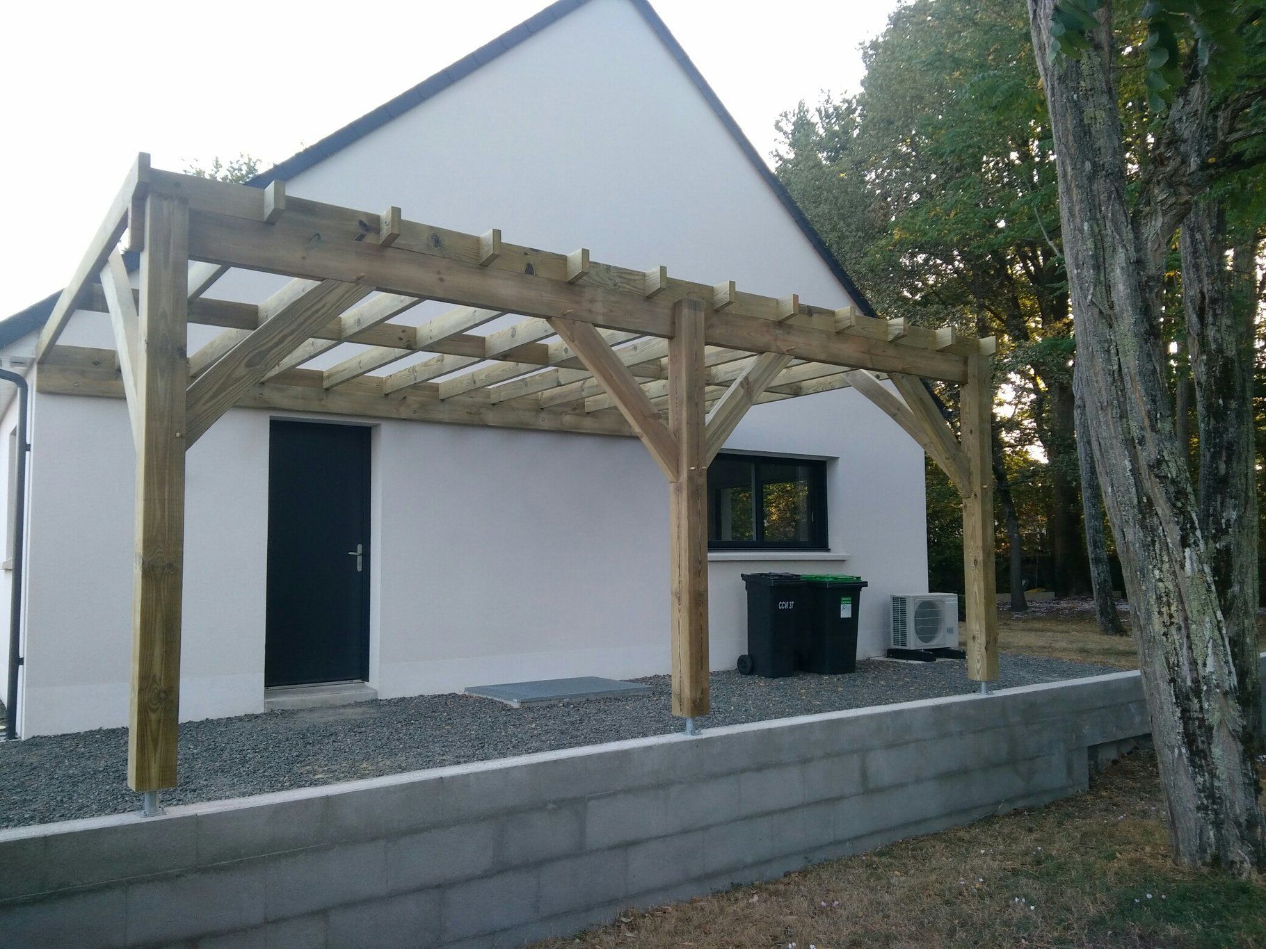 Pergola en bois acollée à une maison blanche