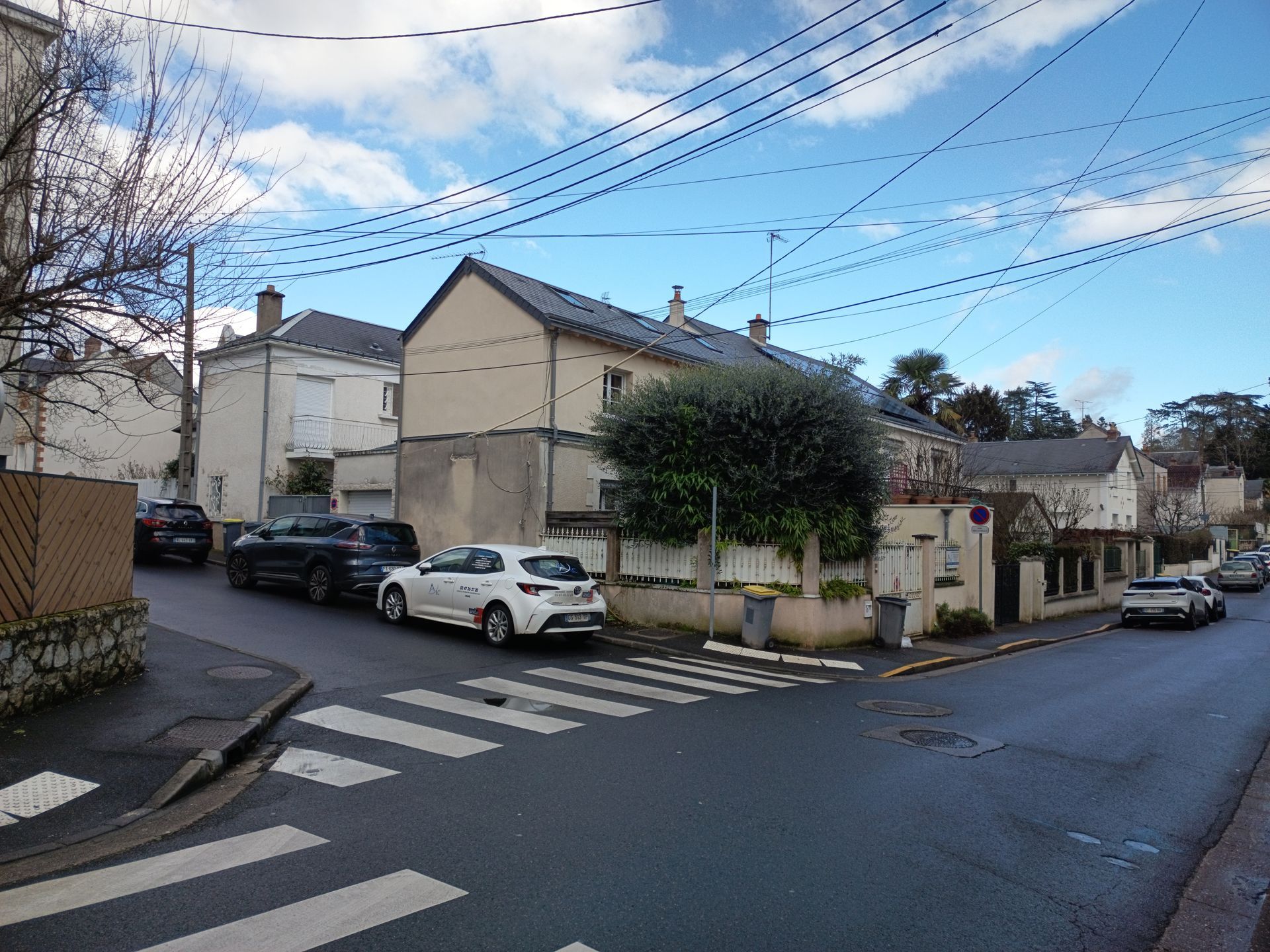 Maisons de quartier avec un croisement de rues, des passages piétons et des véhicules garés