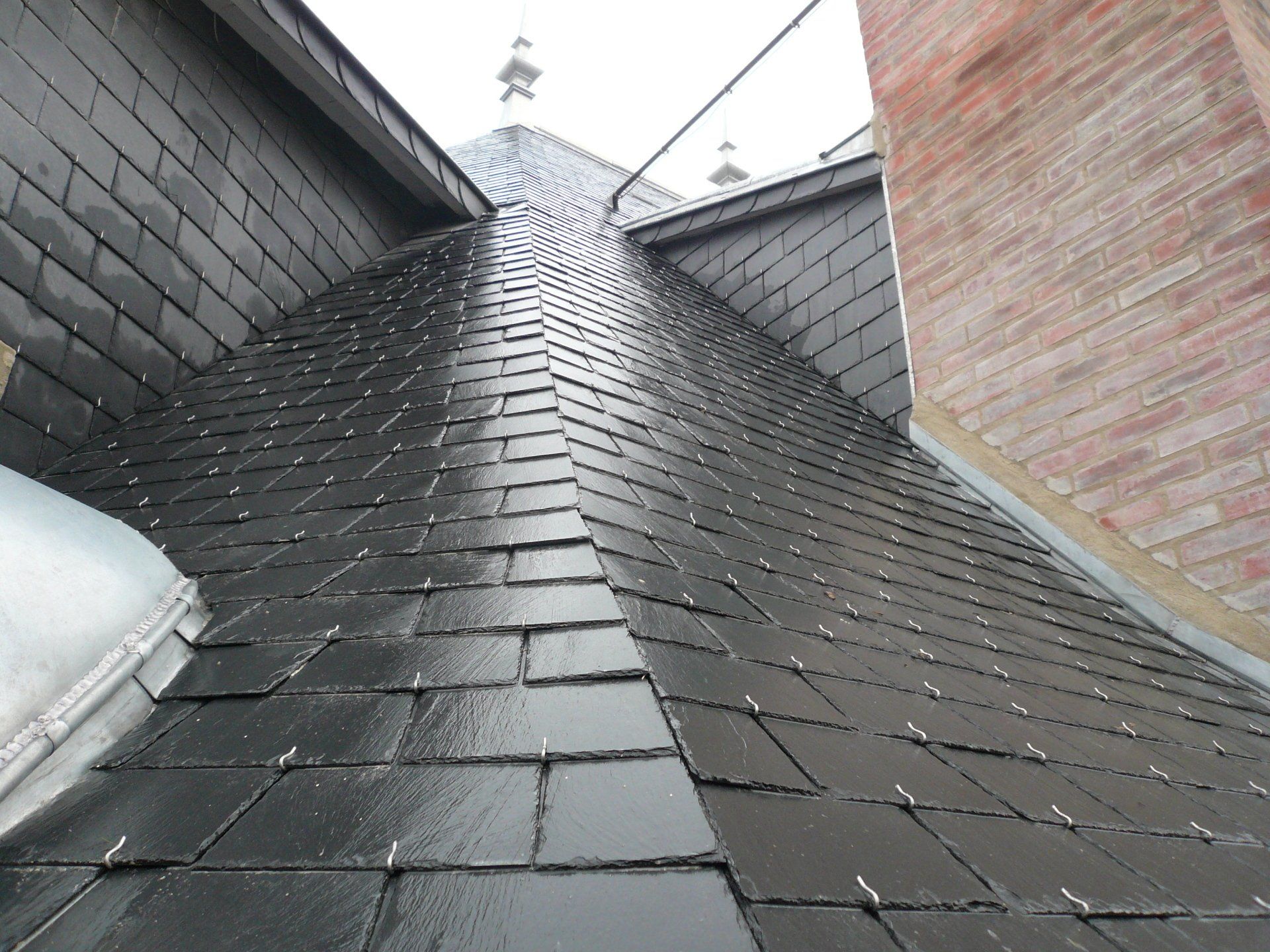 Gros plan sur l'arêtier d'une toiture en ardoise mouillée