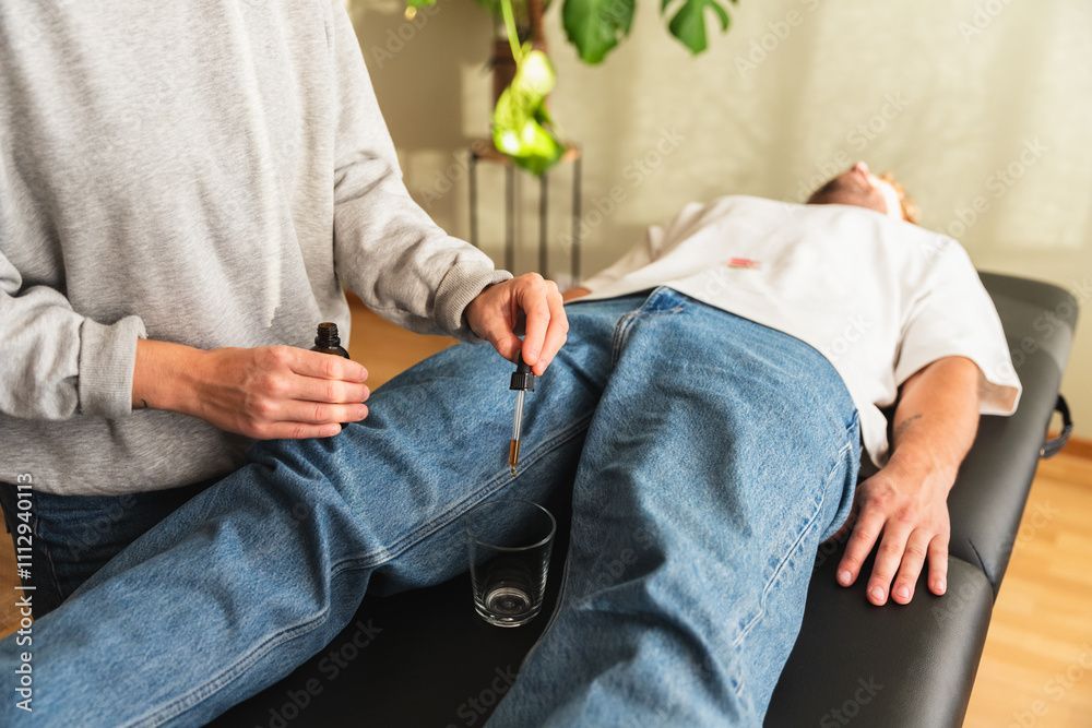 Eine Person liegt auf einer Behandlungsliege, während eine andere ein kleines Instrument am Bein ansetzt.