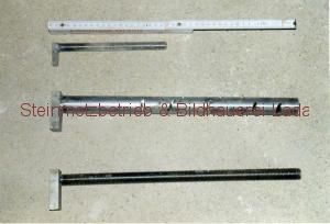 Drei Metallstangen liegen nebeneinander auf einem Tisch.