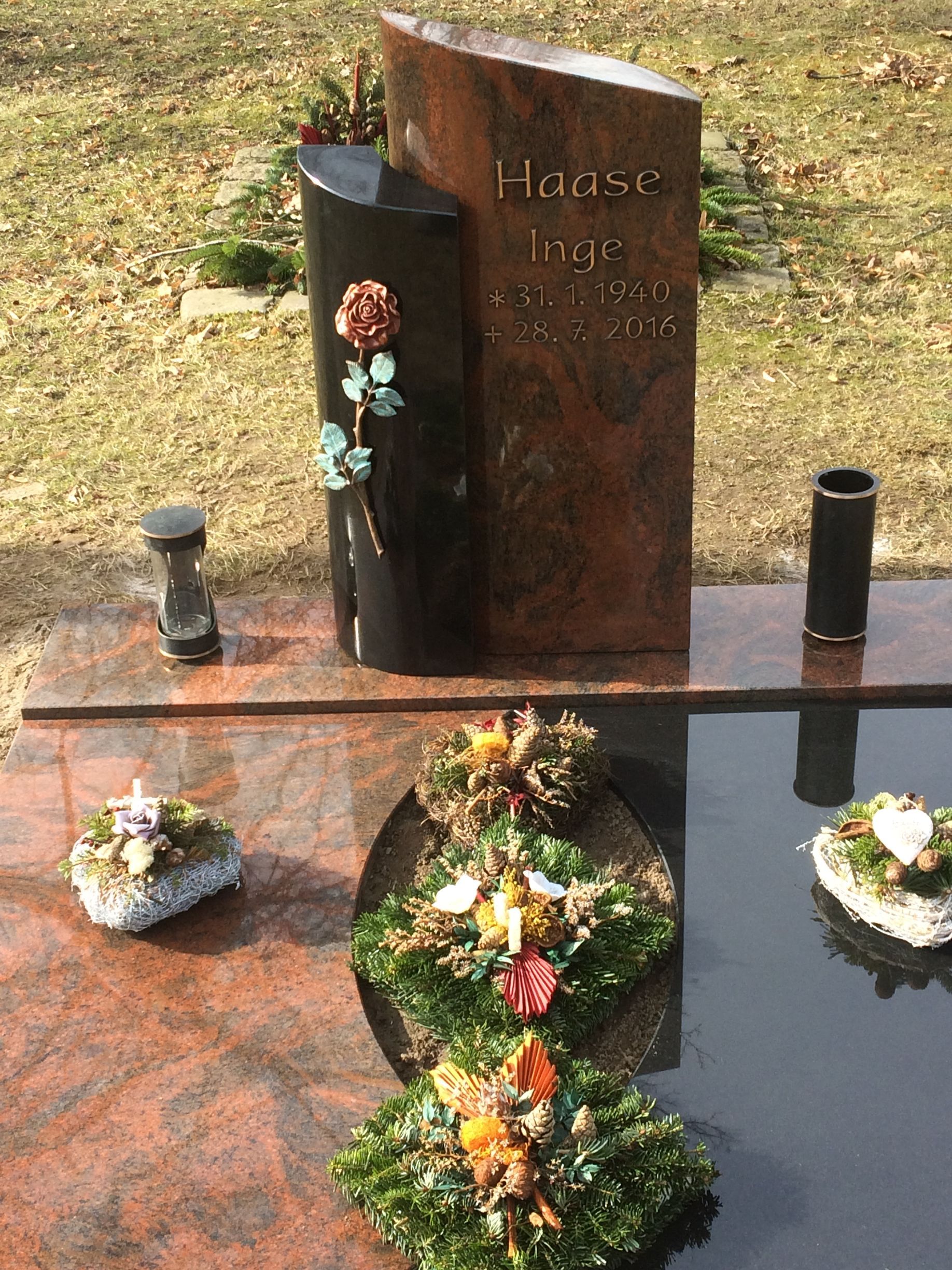 Ein Grab mit Blumen und einer Vase mit der Aufschrift „Hause“