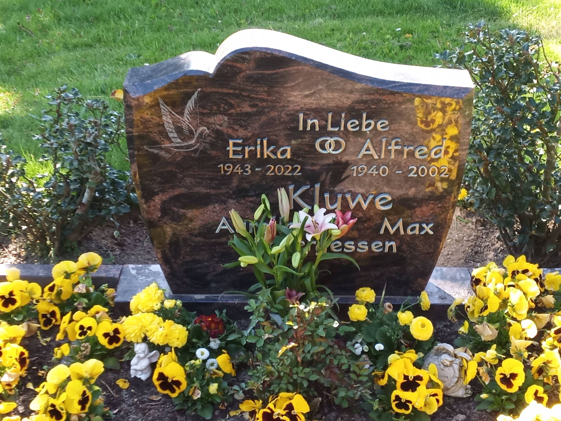 Ein Grabstein für Erika und Alfred ist von gelben Blumen umgeben