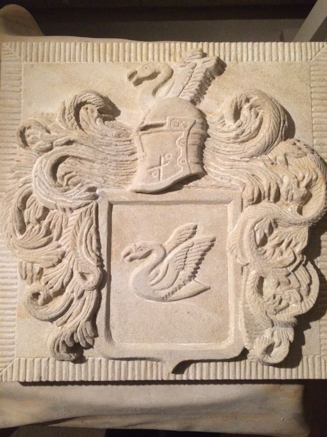 Eine Steinschnitzerei eines Wappens mit einer Ente und einem Helm