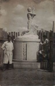 Ein Schwarzweißfoto von zwei Männern, die neben einer Statue stehen.