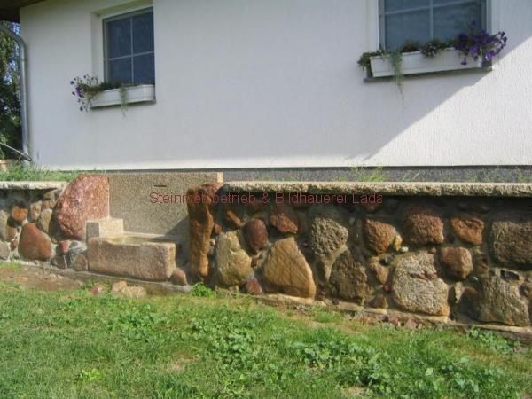 Ein weißes Haus mit einer Steinmauer davor
