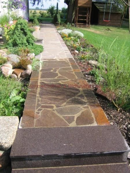 Ein Steinweg mit Stufen, der zu einem Haus führt